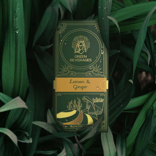 A green tea box with a gold border, featuring a lemon and ginger green tea illustration. The box is surrounded by green leaves and has a design of a woman working in a field.
