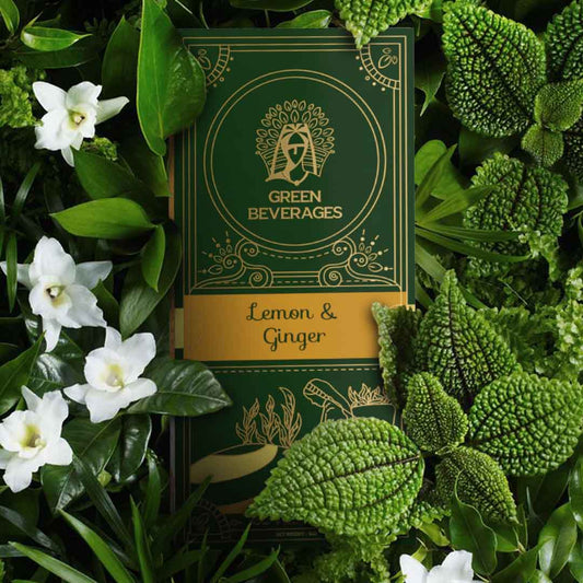 A Lemon and Ginger Green tea box with a gold border. The box is surrounded by green leaves and white flowers. The text on the box reads "Green Beverages" and "Lemon & Ginger."