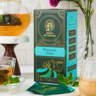 A box of Moroccan mint tea from Green Beverages, featuring a green and gold design. The box includes 27 pyramid tea bags and is part of Herbal Collection. This refreshing tea is known for its relaxing and invigorating properties.