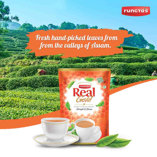 A red tea packet with the brand name "Rungta's Real Gold" and the phrase "A selection of the finest teas, blended for Strength & Aroma." The image depicts a steaming cup of tea, a tea bag, and fresh tea leaves against a backdrop of lush green tea plantations in Assam, India. The text on the packet highlights the use of fresh, hand-picked leaves from the valleys of Assam.